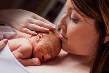 close-up of a mother holding her newborn to her chest