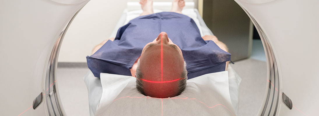 an older white man is seen from the perspective of a CT scanner