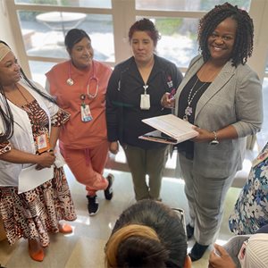 Shaneaya Garner stands to the right of the image as a group of 4 nurses look smilingly at her