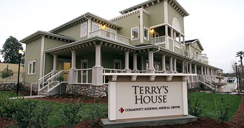 Exterior view of a large, two-story home with a sign reading "Terry's House" in the foreground.